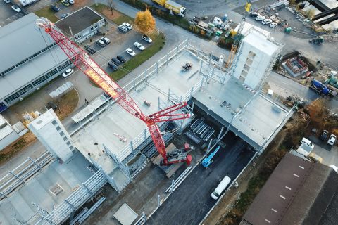 Assembly of steel and concrete elements for a parking garage with the help of a 250-tonne mobile crane.